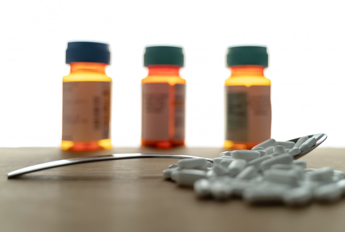 3 prescription bottles and a spoon full of pills