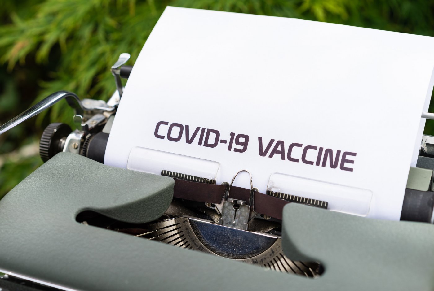 a typewriter with a paper with the text COVID-19 VACCINE