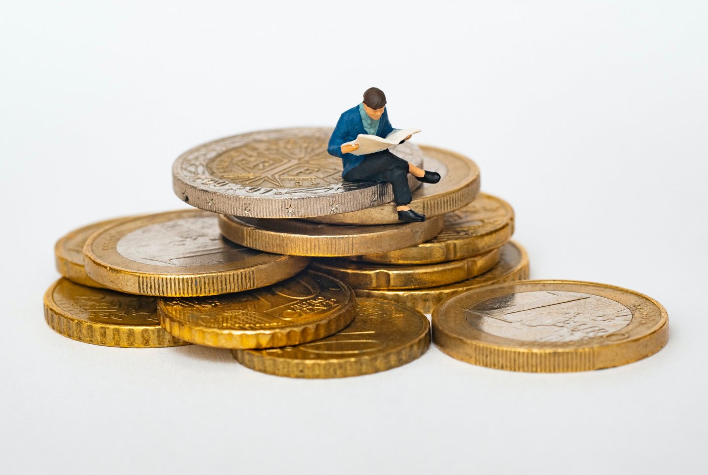 a figure of a man sitting on coins reading a newspaper