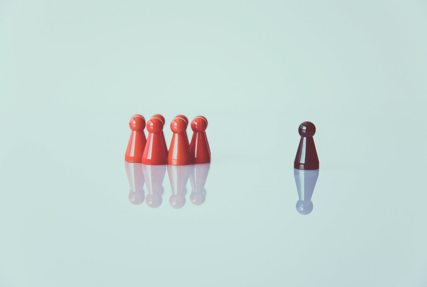 a group of red chess pawns and one black seperated