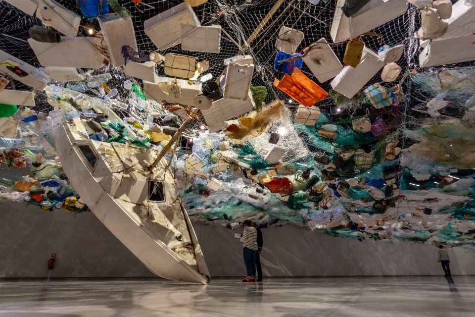 to mennesker, der står nær en mur ved et moderne kunstværk