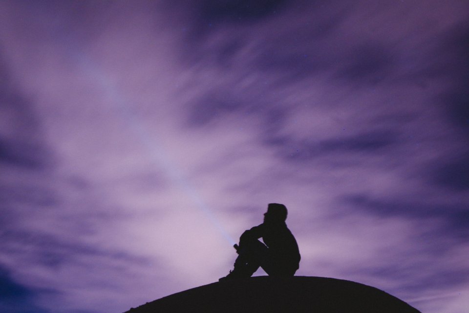 a man siting on a black surface looking at the sky photo 