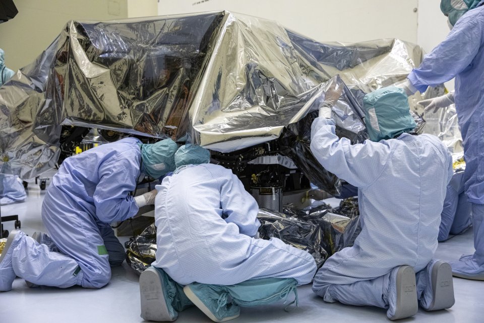 4 man in protective suits unbagging the mars rover