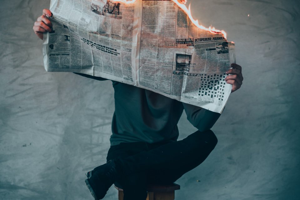 a man reading a newspaper in flames