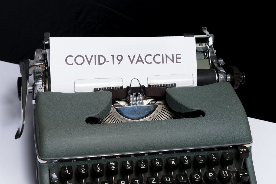 a typewriter with a paper with the text COVID-19 VACCINE